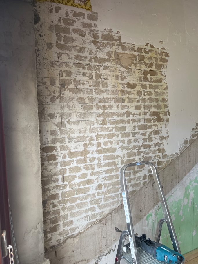 Freigelegte Innenwand mit sichtbarem Ziegelmauerwerk vor dem Durchbruch; vorbereitende Arbeiten zum Öffnen einer tragenden Wand.