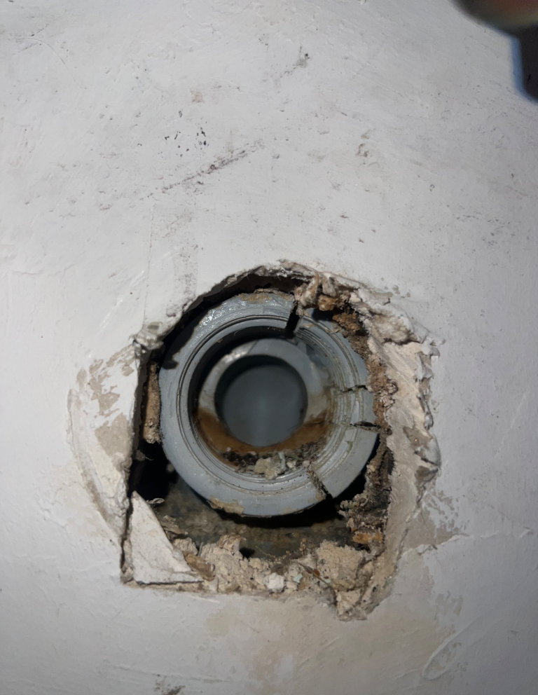 Freigelegte Rohrleitung in einer Wand mit sichtbarer Undichtigkeit während eines Sanitär-Notdiensteinsatzes