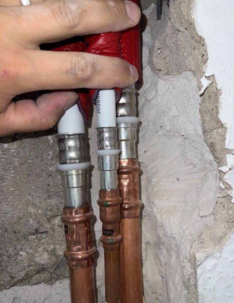 Undichte oder beschädigte Warmwasser- und Kaltwasserleitungen mit sichtbarer Korrosion und Pressverbindungen während eines Sanitär-Notdienst